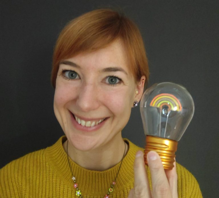 Gör vårt kostnadsfria nivåtest i svenska Rebecca Mattsson med en glödlampa mot grå bakgrund symboliserar Sweasifys nivåtest i svenska.
