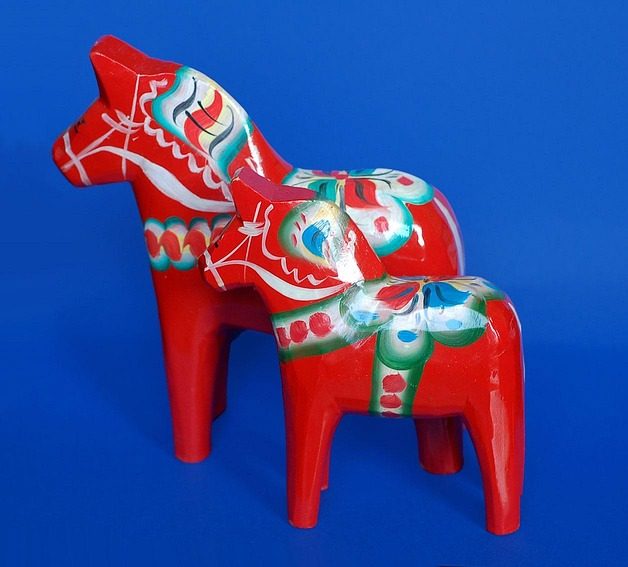 Två röda dalahästar mot blå bakgrund symboliserar Sweasifys nivåtest i svenska.